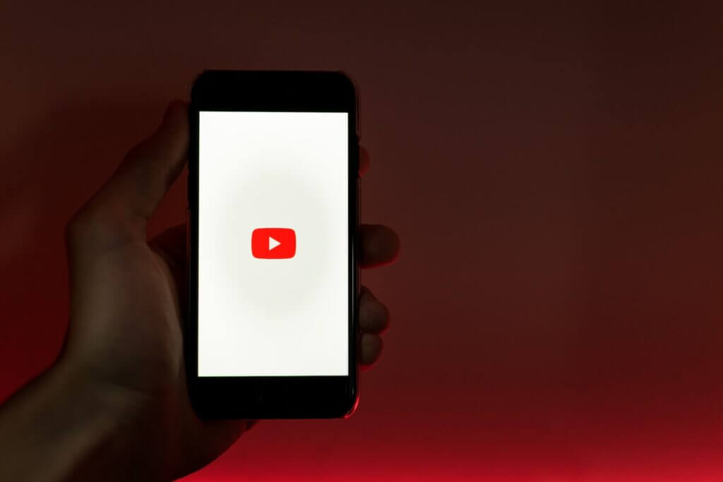person hand holding smartphone with youtube logo